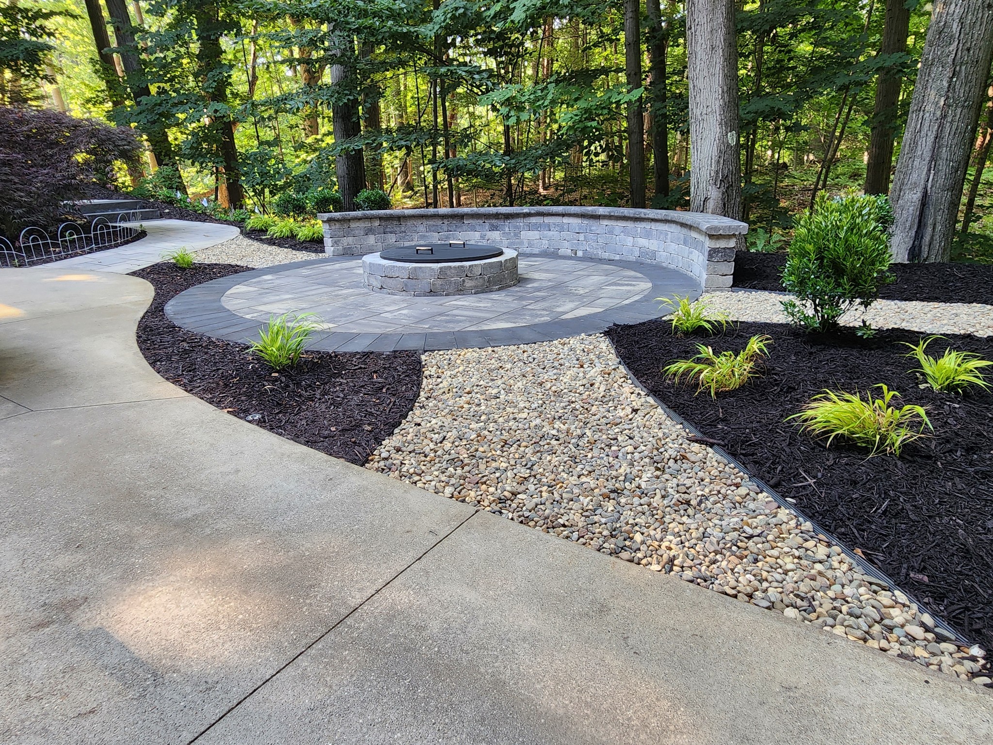 Fire pit with curved seating wall surrounded by landscaping